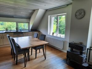 a kitchen with a table and chairs and a clock on the wall at Superbe Appart' Bois De Fagne in Malmedy