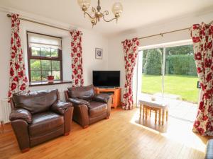 a living room with two leather chairs and a television at Tilladavin House in Tomhaggard