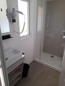 a white bathroom with a shower and a sink at mobil home neuf dans camping 4* avec piscine in La Plaine-sur-Mer
