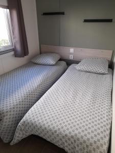 two beds sitting next to each other in a bedroom at mobil home neuf dans camping 4* avec piscine in La Plaine-sur-Mer