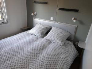 um quarto com uma cama branca e 2 almofadas em mobil home neuf dans camping 4* avec piscine em La Plaine-sur-Mer