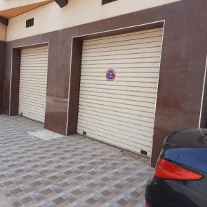Deux portes de garage dans un bâtiment avec une voiture garée devant dans l'établissement GRAND APPARTEMENT Au calme, ORAN -ALGERIE, à Oran
