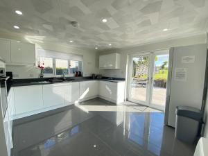 una cucina con armadi bianchi e soffitto piastrellato di Buena Vista a Tintagel