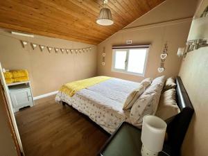a bedroom with a large bed and a window at Bumble Bee Cabin in South Cerney