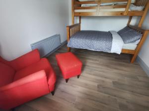 a bedroom with a bed and a red chair at Orchard Cottage in Wexford