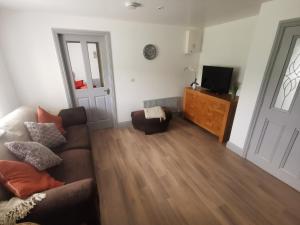 a living room with a couch and a television on a dresser at Orchard Cottage in Wexford