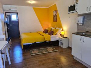 a bedroom with a bed with yellow sheets and a kitchen at Apartments Šeherzada in Pula