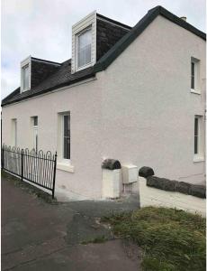 a white house with a fence in front of it at 4 bed bungalow near Airport in Edinburgh