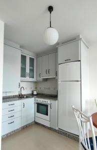 a kitchen with white cabinets and a white refrigerator at Casa Charo - Sardiñeiro in Fisterra