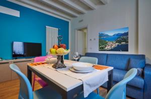 uma sala de jantar com uma mesa e um sofá azul em Lecco Lake Apartments Villa Liberty em Lecco