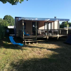 a small cabin with a deck and a table and chairs at mobil home neuf dans camping 4* avec piscine in La Plaine-sur-Mer