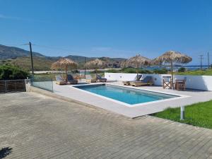 una piscina con sedie e ombrelloni su un patio di Achilli Apartments a Skiros