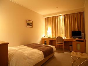 Habitación de hotel con cama y escritorio con ordenador en Kitami Pierson Hotel - Vacation STAY 54802v, en Kitami