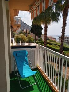 une chaise bleue assise sur un balcon avec des palmiers dans l'établissement Eliana Appartment, à Menton