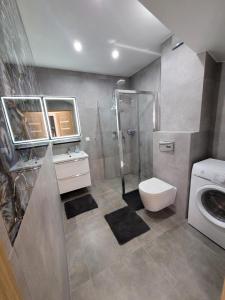 a bathroom with a shower and a toilet and a sink at Apartament MiMi - Dziwnówek Horizon Park , 2 sypialnie i salon in Dziwnówek