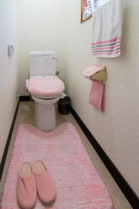 a bathroom with a toilet and pink slippers on the floor at Siawase no yado - Vacation STAY 68283v in Fuefuki