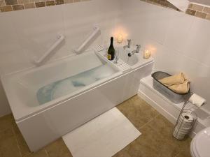 een badkamer met een bad en een fles wijn bij “ Nicky’s Retreat! Warm and quirky seaside flat! in Porthcawl