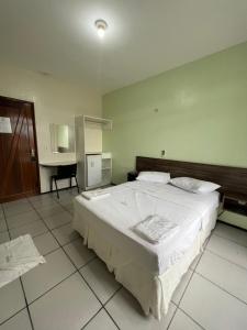 a bedroom with a large white bed and a desk at Hotel Pinheiro in Ibiapina