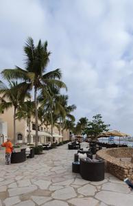 une personne debout en face d'un complexe avec des palmiers dans l'établissement WASAN LUXURY RESIDENCE HAWANA Salalah, à Salalah