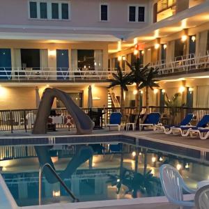 un hotel con una piscina con sillas y un edificio en Beach Colony Motel, en Wildwood Crest