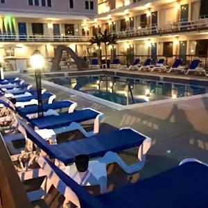 a swimming pool with blue lounge chairs in a hotel at Beach Colony Motel in Wildwood Crest