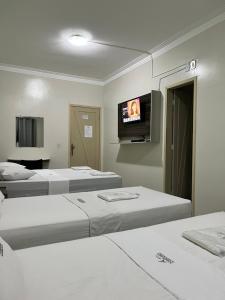 a room with three beds and a flat screen tv at Hotel Pinheiro in Ibiapina