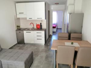 uma cozinha e sala de jantar com armários brancos e uma mesa em Apartmani Grabovčić em Punat