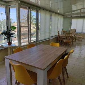 a dining room with a wooden table and yellow chairs at ATICO EN SAN JOAN DE ALICANTE in San Juan de Alicante