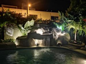 a swimming pool with a waterfall in a backyard at night at Departamentos con Alberca in Mazatlán