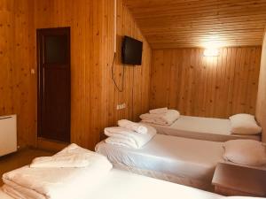 a room with three beds in a wooden wall at Uğur Motel in Uzungöl
