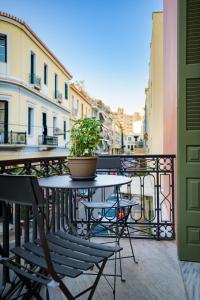 einen Tisch und Stühle auf einem Balkon mit Topfpflanze in der Unterkunft Urban Tales in Athen