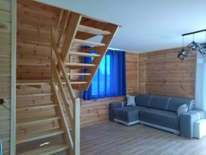 a living room with a staircase and a blue couch at Domki Jastrzębia Mazury in Pasym