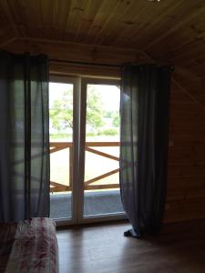 a bedroom with a large window with curtains in front at Domki Jastrzębia Mazury in Pasym