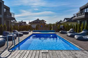 a swimming pool on a wooden deck with houses at La Mer Palanga apartamentai su baseinu ir terasa in Palanga