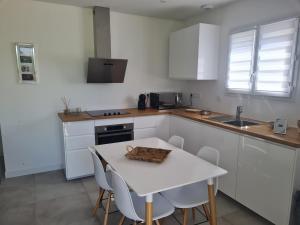 - une cuisine avec des placards blancs, une table et des chaises dans l'établissement Location "Casa Monna", à Prunelli-di-Fiumorbo