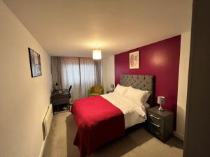 um quarto com uma cama com uma parede vermelha em Spacious 1 bed relocation apartment free parking, em Brierley Hill