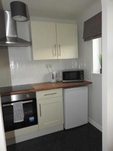 a kitchen with white cabinets and a black microwave at Serviced Accommodation in Hull