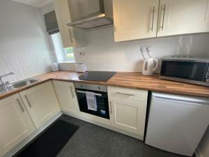a kitchen with white cabinets and a sink and a microwave at Serviced Accommodation in Hull