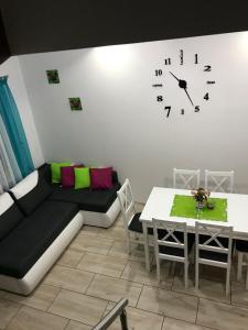 a living room with a couch and a clock on the wall at Delfinek - Domki Apartamenty in Gąski