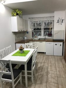 a kitchen with a white table and chairs at Delfinek - Domki Apartamenty in Gąski