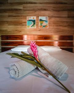 a pink flower sitting on top of a bed at Pousada Canto do Dado Praia de Itamambuca in Ubatuba