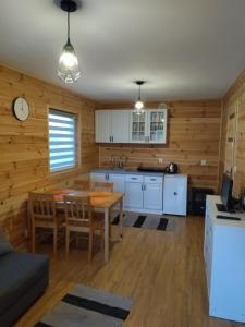 a kitchen and living room with a table and chairs at Domki Jastrzębia Mazury in Pasym