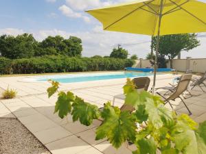 a yellow umbrella and chairs next to a swimming pool at La Grue Gites in Mons