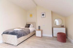 a bedroom with a bed and a mirror and a stool at Dior House Apartments in Leeds