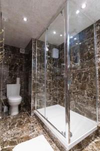 a bathroom with a toilet and a glass shower at Dior House Apartments in Leeds