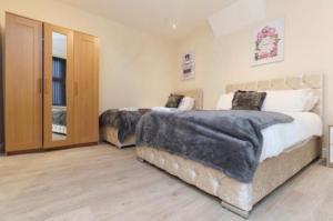 a bedroom with two beds and a wooden floor at Dior House Apartments in Leeds