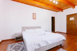 a bedroom with a bed with white sheets and a wooden ceiling at Pensiunea LUKA Slanic Moldova in Slănic-Moldova