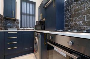 a kitchen with blue cabinets and a washer and dryer at Dior House Apartments in Leeds