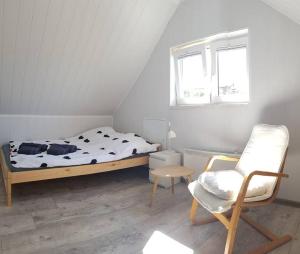 um quarto com uma cama, uma cadeira e uma janela em CLAUDIA Domek na Kaszubach em Sławki