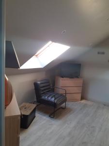 um quarto no sótão com uma cadeira e uma clarabóia em Le Rêve de Marcel em Le Molay-Littry
